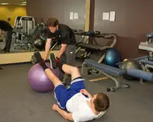 personal training, Mark Foley of Inner Evolution FItness, helping a client with form on a stability ball